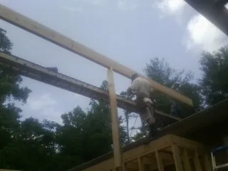 Carpenter setting a ridge beam over a new addition frame — Ice Dam Removal by Roofing Brothers in Corrigan