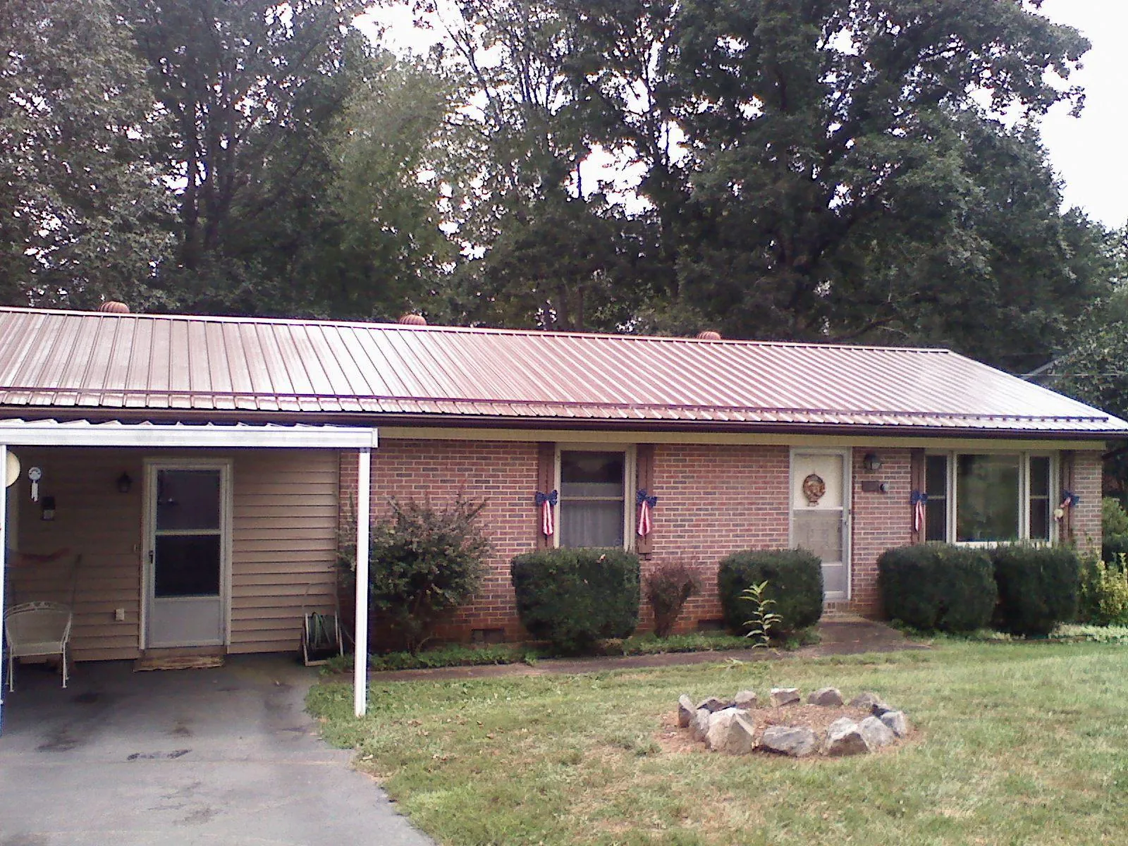Bronze metal roof and carport on a brick ranch home — Roof Repair work by our crew in Corrigan
